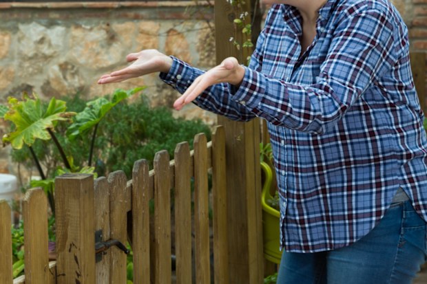 Angry woman quarreling with her male neighbor, talking through wooden fence