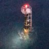 A passing ship spotted the man standing at the top of a marine navigation beacon. 