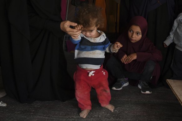 Australian women and children watch as Omeid, aged 1 yr and 7 months, is assisted in walking in al-Hawl camp.