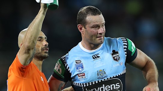 Boyd Cordner is helped from the field by Roosters and Blues trainer Travis Touma.