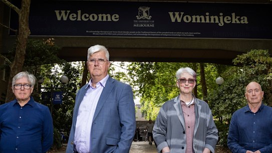 L-R: University of Melbourne Faculty of Arts professors David Nichols, Christopher Marshall, Alison Young and Philip Goad stand in front of the archway of the John Medley Building. A graduating student poses for a photo behind them.