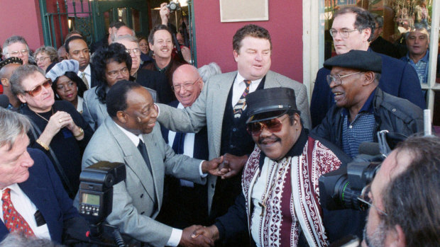 Fats Domino, centre right, shakes hands with Dave Bartholomew, right, amid a crowd of former colleagues at the 50th anniversary observance of Domino's first recording session in New Orleans in December 1999. 