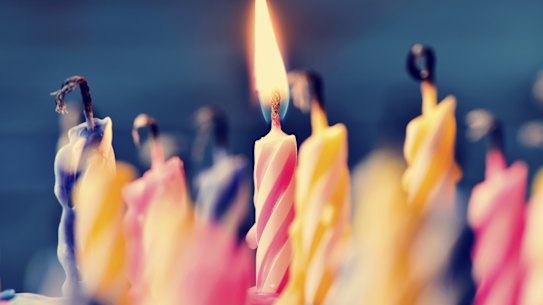 closeup of some unlit candles and just a lit candle after blowing out the cake Birthday candles