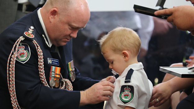 RFS Commissioner Shane Fitzsimmons pins the service medal of Geoffrey Keaton onto his son, Harvey.