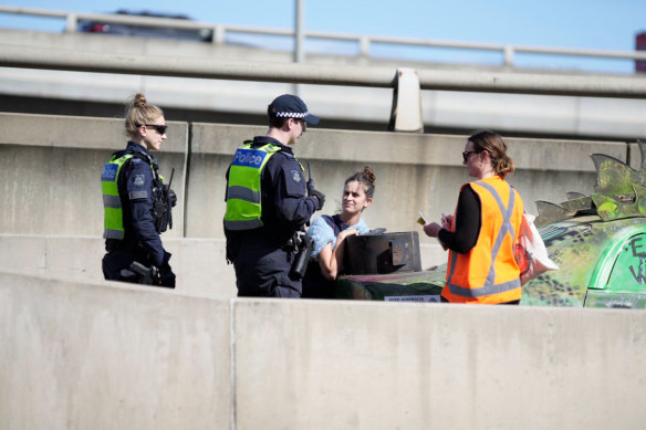 Police officers speak to women disrupting traffic on the West Gate Freeway on Saturday.