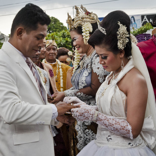 A bride and groom exchange wedding rings in Yogyakarta.