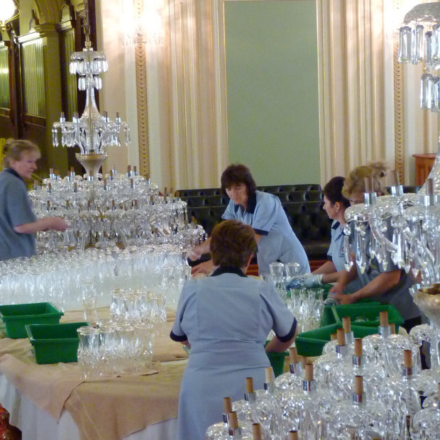 A team cleans the chandeliers by hand. 