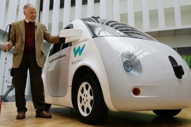 Steve Mahan, who is blind, stands by the Waymo driverless car during a Google event, 