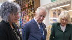 Charles and Camilla look at their throne seat covers during a visit to the Royal College of Needlework at Hampton Court Palace.