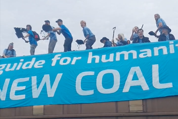 Activists shovel coal out of a train carriage in the Newcastle suburb of Sandgate on Sunday.