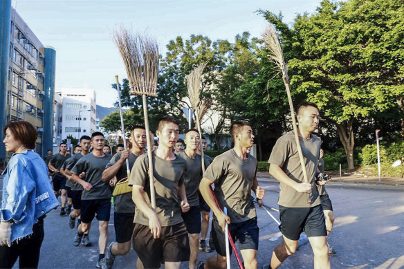 People’s Liberation Army soldiers, with brooms, arrive to clean up the protest area at Hong Kong Baptist University in Hong Kong, on Saturday. 