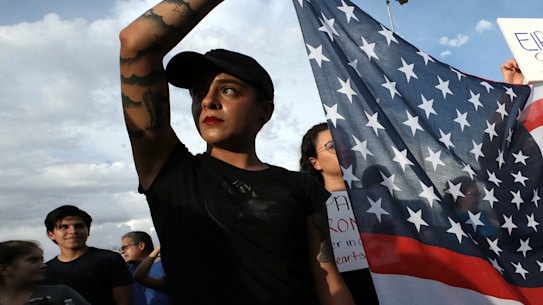 Twin sisters Jessica Torres, left, and Danielle Novoa hold an American flag during the Hope Border Institute prayer vigil for the victims of Saturday's mass shooting at a shopping complex in El Paso, Texas.