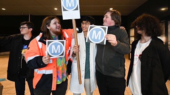 Thomas Marynissen, Wesley Fung, and Logan Newboult-Kosztyo with Metro signs are waiting for the first Metro train on the M1 line at Sydenham Station. 