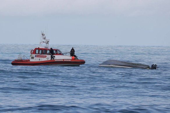 A coastguard boat with the capsized boat off Kaikoura.