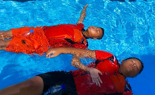 Children practise floating at a pool in Surat Thani using a second hand water bottle as a flotation device. 