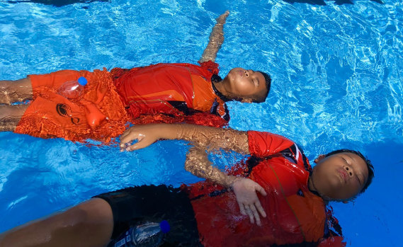 Children practise floating at a pool in Surat Thani using a second hand water bottle as a flotation device. 