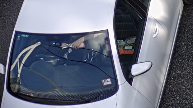 A man prepares to inhale nitrous oxide while speeding down the highway.