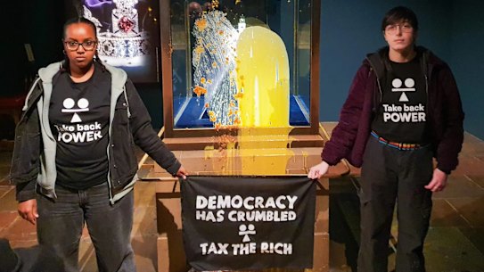 Take Back Power supporters pose alongside the Crown Jewels case at the Tower of London.