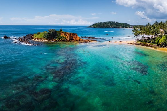 Aerial panorama of the tropical beach and clear sea with coral reefs in the town of Mirissa, Sri Lanka.