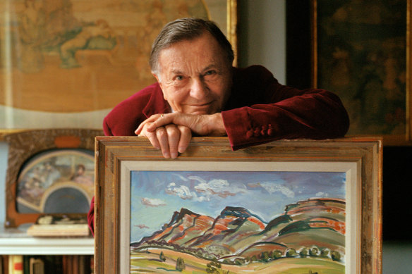 Barry Humphries at home in 2021 with his own painting, a landscape of Wilpena in South Australia.