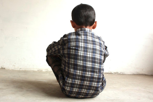 A generic image of a young boy sitting alone in an empty room.