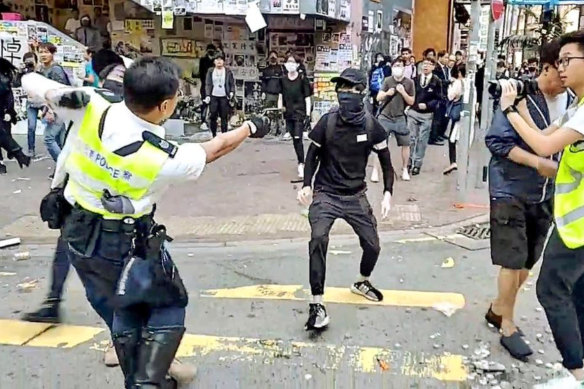 The video captures the moment a Hong Kong policeman holds onto one protester and shoots a second protester, who was later hospitalised.