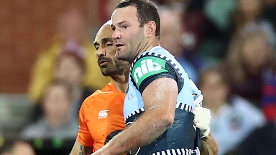 Boyd Cordner is helped from the field by Roosters and Blues trainer Travis Touma.