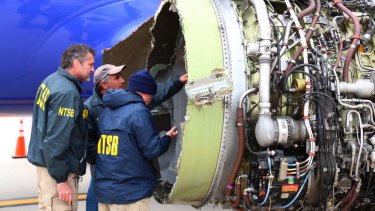 National Transportation Safety Board investigators examine damage to the engine of the Southwest Airlines plane.