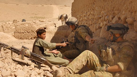 An Afghan boy sits with Australian Reconstruction Task Force soldiers during a meeting with local leaders in Oruzgan Province, Afghanistan.