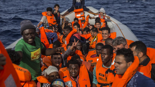 Migrants aboard a rubber dinghy off the Libyan coast are provided with life vests by rescuers aboard the Open Arms aid boat last year.