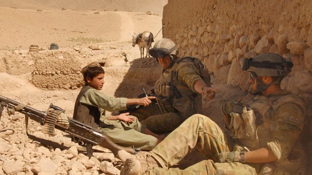 An Afghan boy sits with Australian Reconstruction Task Force soldiers during a meeting with local leaders in Oruzgan Province, Afghanistan.