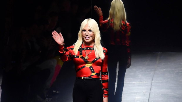 Donatella Versace waves to the audience at the end of the presentation of her Fall/Winter 2019/20 collection at Milan Men's Fashion Week.