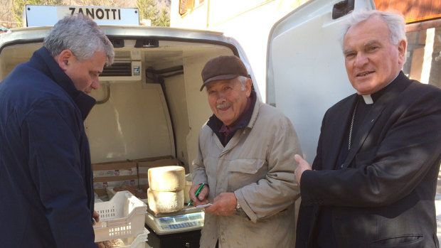 Monsignor Konrad Krajewski, right, stands with a cheese maker in Camerino, central Italy.
