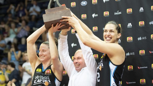 The Canberra Capitals' Kelsey Griffin, Paul Goriss, and Marianna Tolo hoist the WNBL championship trophy.