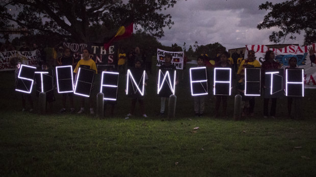 Aboriginal children hold LED signs up to spell the slogan of the protest.