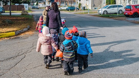 A daycare group walks through a residential neighbourhood in Quebec, where childcare has been unvirsal and provided at a fixed rate per day for more than 25 years.