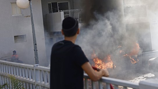 A resident looks at cars on burning after a during a rocket attack in Ashqelon, Israel.