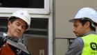 Better Regulation Minister Kevin Anderson, left, inspects a sheet of cladding at the apartment building in Darlington on Tuesday.