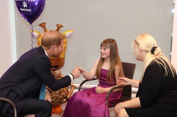 Prince Harry visits with a young person at the WellChild charity event.