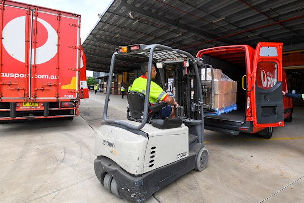 Workers pack Australia Post delivery trucks and vans