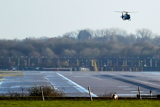 A police helicopter flies over the runway at Gatwick Airport, London, as the airport remains closed with incoming flights delayed or diverted to other airports, after drones were spotted.