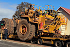 The giant trucks squeeze past houses, businesses and schools.