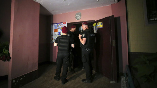 Police guard the front door of the apartment block where Arkady Babchenko was killed.