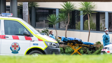 Ambulance paramedics push a stretcher into the St Basil's Home for the Aged facility in Fawkner.