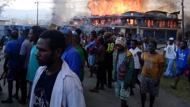 People gather as shops burn in the background during a protest in Wamena in Papua province, Indonesia, on Monday.