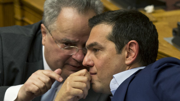 Greek Prime Minister Alexis Tsipras, right, chats with Greek Foreign Minister Nikos Kotzias during a parliamentary session, in Athens, on Saturday.