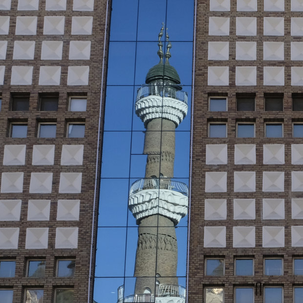 The minarets of the Urumqi International Grand Bazaar Mosque are reflected on nearby building. Taking pictures of mosques, government buildings, and police is prohibited in Urumqi, a local police officer tells us.