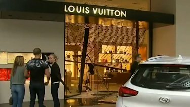Police say two men, with their faces covered, repeatedly reversed a hatchback car into the store before one jumped out and loaded items into the car.