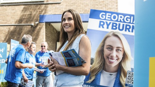 Much in common but only one victor: Jacqui Scruby on polling day, flanked by the poster of her Liberal rival, Georgia Ryburn.