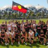 Collingwood players and staff with the Aboriginal flag.